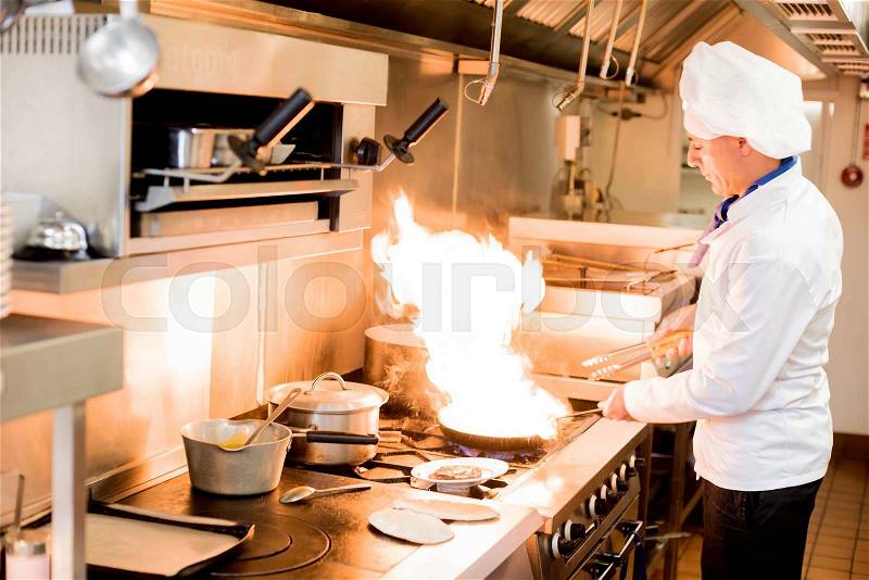 Male chef cooking in a frying pan on a kitchen , stock photo