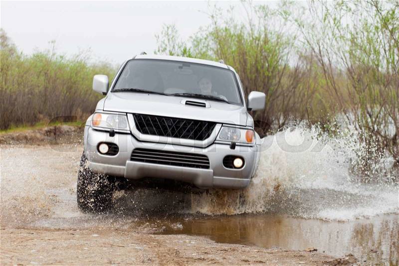 Car moving by water making lots of splashes with a woman driver, stock photo
