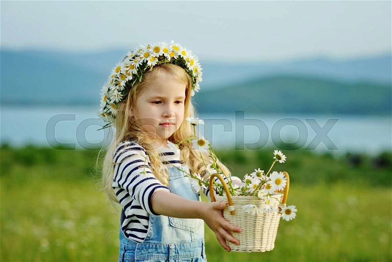 Girl with daisies in basket and on the head, stock photo