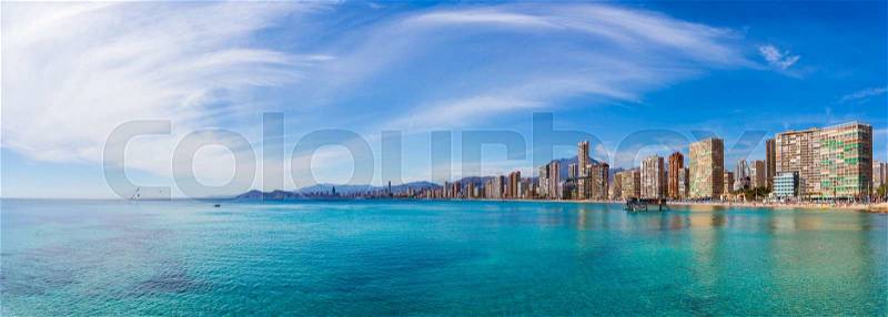 Panorama of the coast of the city with beautiful sky with clouds and clear blue water on the background of urban buildings and mountains, stock photo