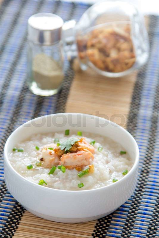 Rice porridge with shrimp, squid on white table, stock photo