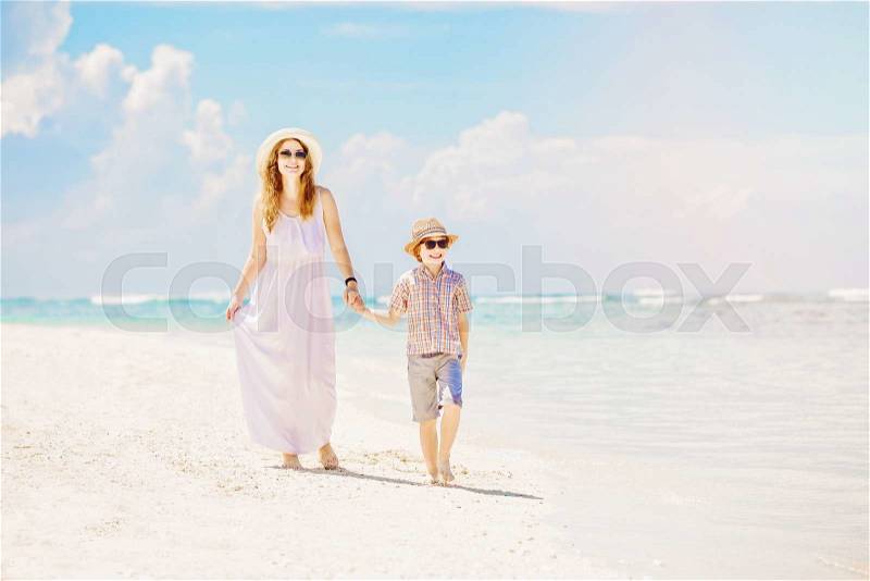 Happy mother and son walk along the white sand ocean beach having great family time on vacation on Pandawa Beach, Bali. Paradise, travel, vacation concept, stock photo
