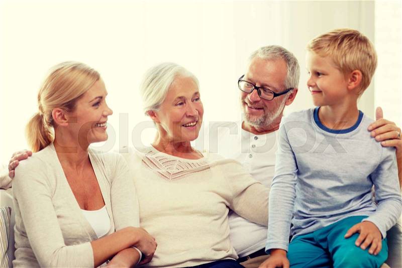 Family, happiness, generation and people concept - happy family sitting on couch at home, stock photo