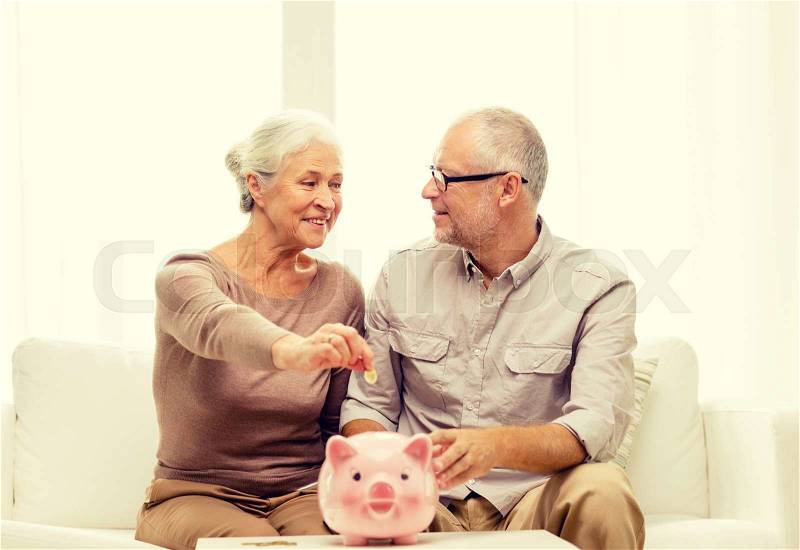 Family, savings, age and people concept - smiling senior couple with money and piggy bank at home, stock photo