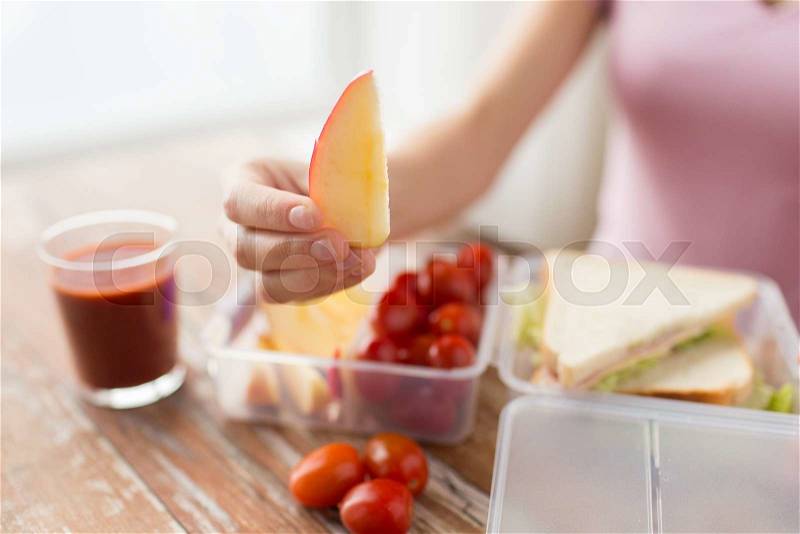 Healthy eating, storage, dieting and people concept - close up of woman with food in plastic container at home kitchen, stock photo