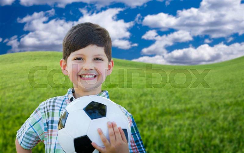 Cute Smiling Young Boy Holding Soccer Ball on Green Grass in the Park, stock photo