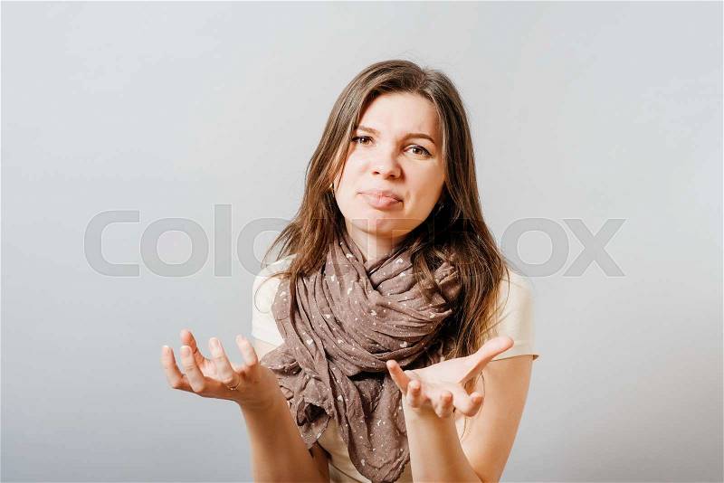 Young woman unhappy asks what you want. On a gray background, stock photo