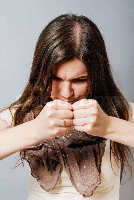 Young woman angry fists. On a gray background, stock photo