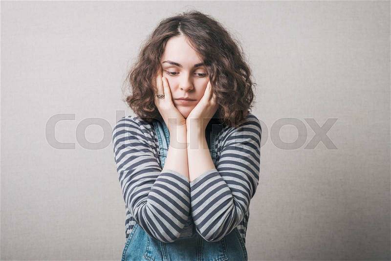 The woman thought, sad, thinking, emotions. On a gray background, stock photo