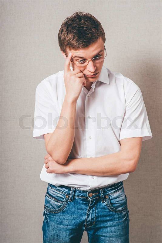 The man in glasses tired thinks. On a gray background, stock photo