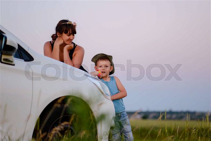 Mother and Son Looking at the Camera While Leaning on the Front of White Car, stock photo