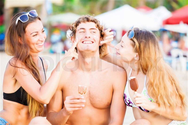 Group of happy young people in bathing suits eating ice cream on the beach and having fun, stock photo