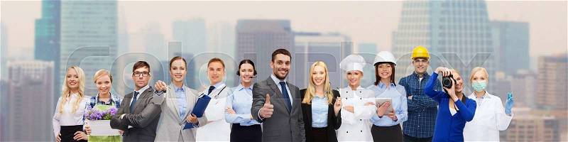 People, profession, qualification, employment and success concept - happy businessman over professional workers showing thumbs up over city background, stock photo