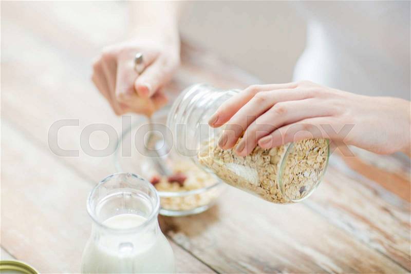 Food, healthy eating, people and diet concept - close up of woman eating muesli with milk for breakfast, stock photo