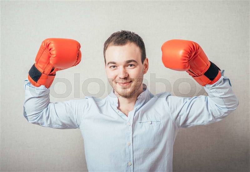 Businessman ready to fight with boxing gloves over gray background. Looking at camera, stock photo