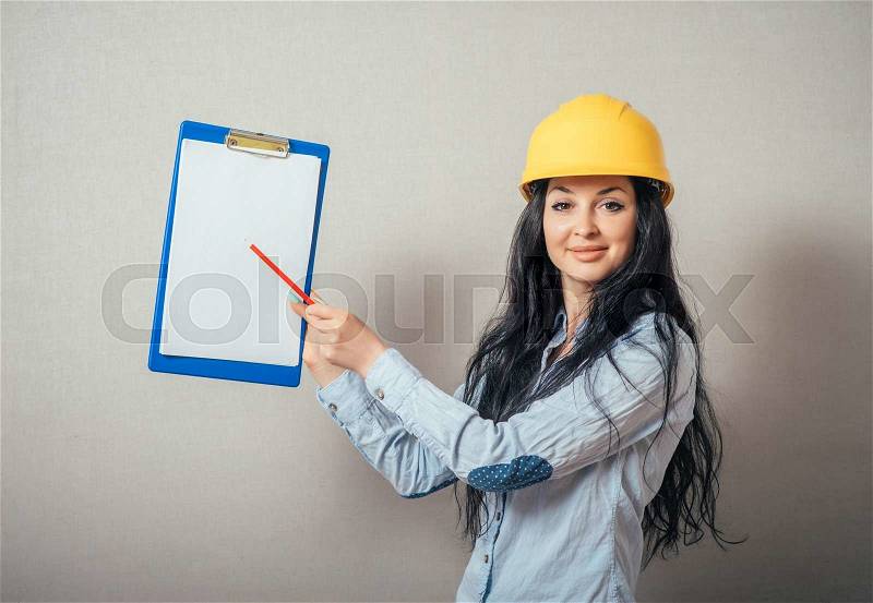 Engineer woman smile, writes in business paper. yellow protective helmet, stock photo