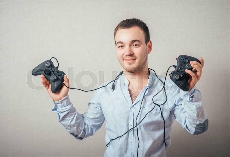 Happy young man in winning pose wearing shirt holding video game joystick, stock photo