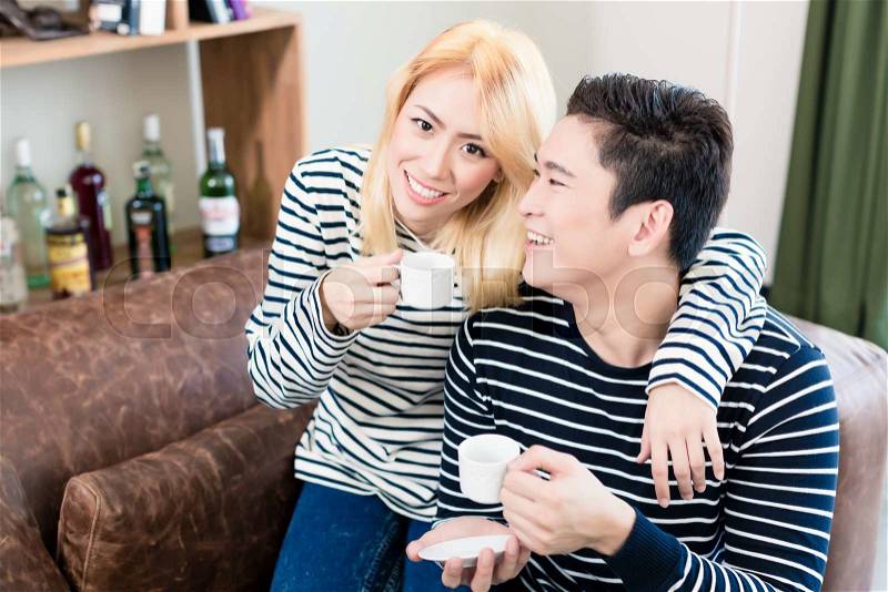 Asian Couple on Sofa drinking coffee together, stock photo