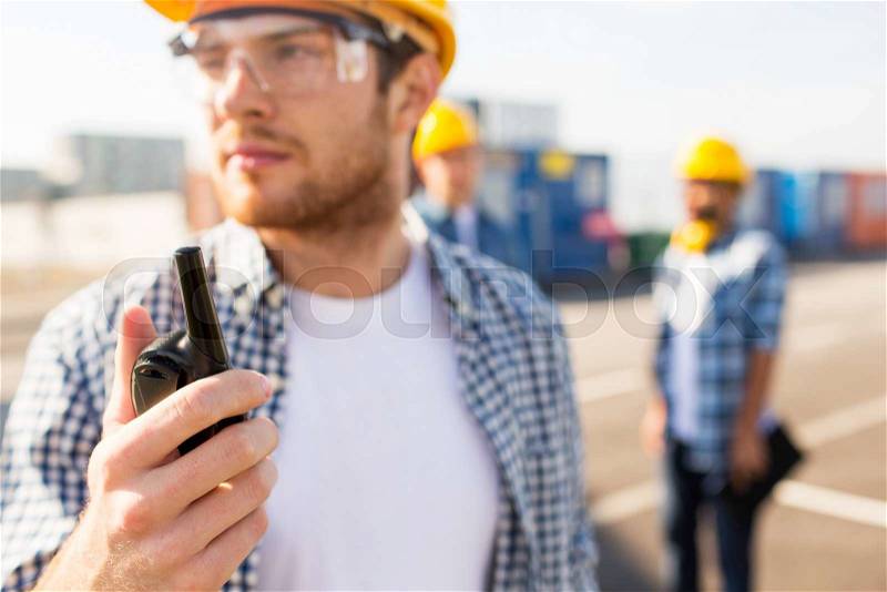 Industry, building, technology and people concept - close up of male builder in hardhat with walkie talkie or radio outdoors, stock photo