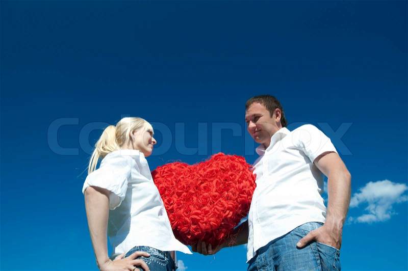 Couple of young people, loving boy and girl holding hands in the heart of roses, stock photo