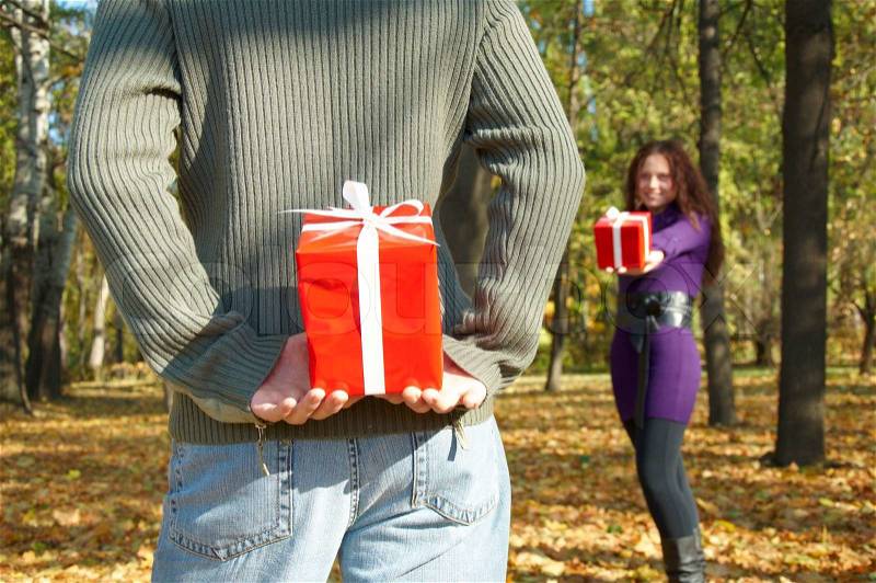 Young couple gives gifts, in the autumn park, stock photo