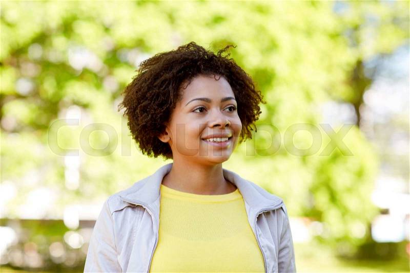 People, race, ethnicity and portrait concept - happy african american young woman in summer park, stock photo