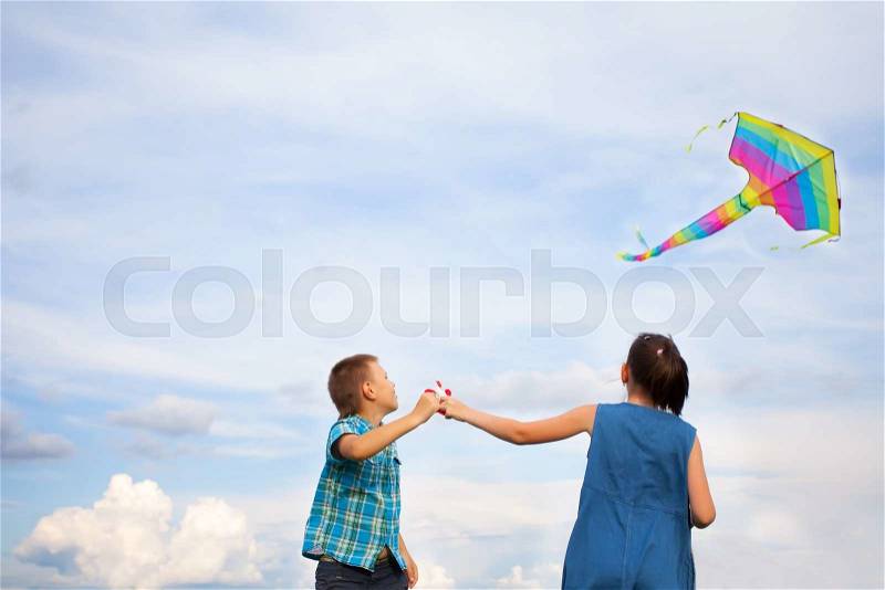 Boy and girl flying kite on a bright summers day, stock photo