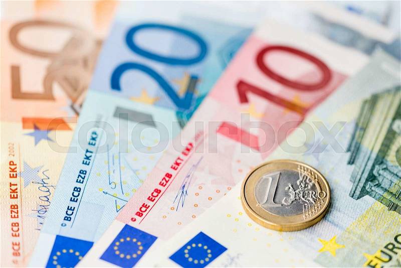 New one euro coin on euro banknotes, stock photo