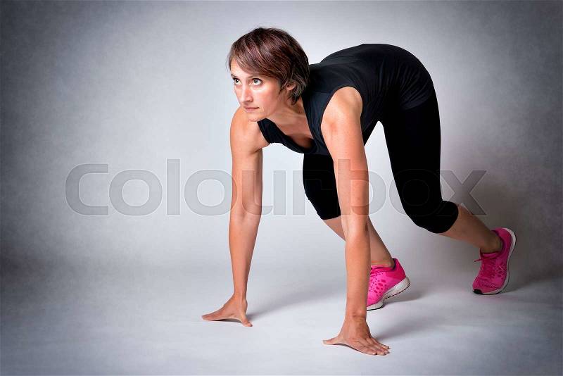 Image of running middle aged handsome woman in running start position, stock photo