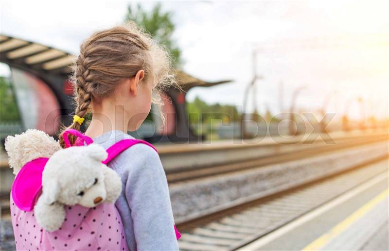 Little girl waiting for train at the railway station, stock photo