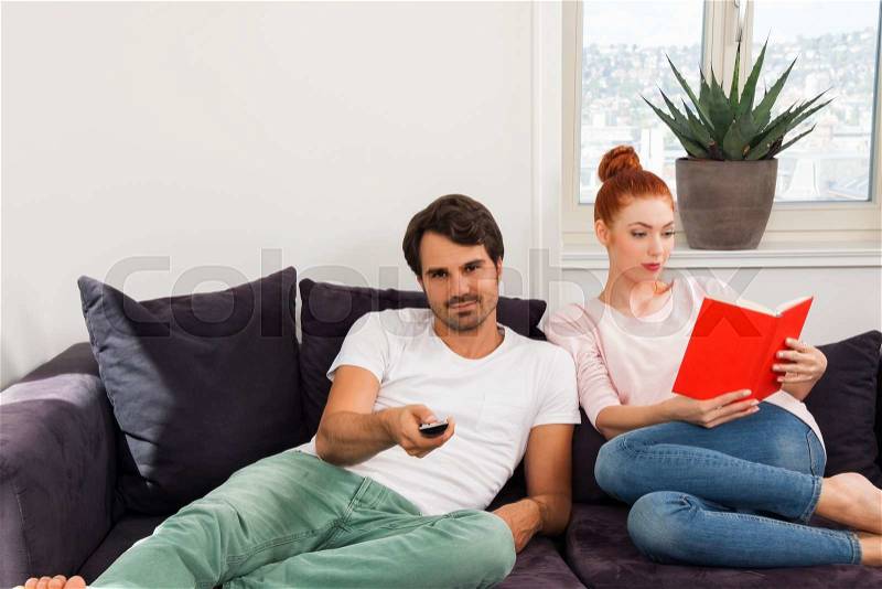 Close up Sweet Young Couple Resting at the Couch in the Living Area While Reading a Book Together Seriously, stock photo