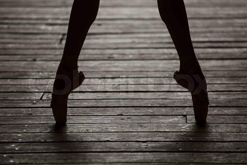 Photo of graceful ballerina dancing feet on the floor in backlit, stock photo