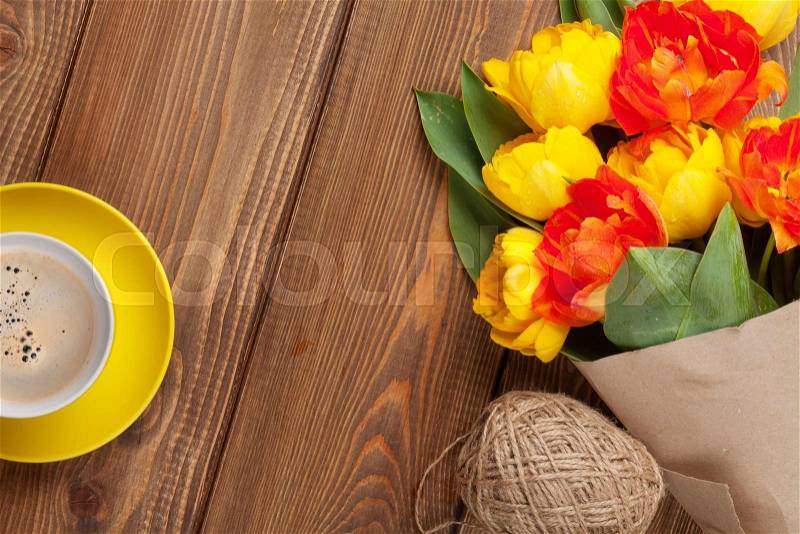 Colorful tulips bouquet and coffee cup on wooden table. Top view with copy space, stock photo