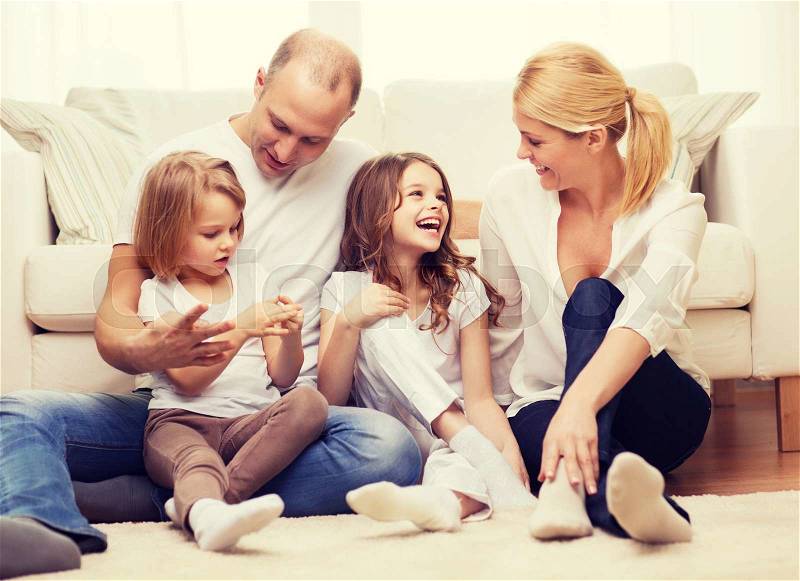 Family, children and home concept - smiling family with and two little girls sitting on floor at home, stock photo