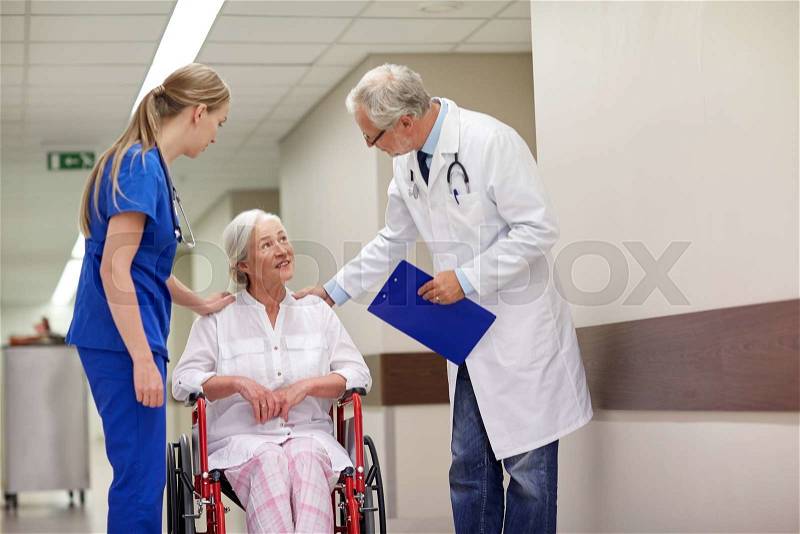 Medicine, age, health care and people concept - doctor, nurse and senior woman patient in wheelchair at hospital corridor, stock photo