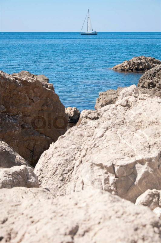 Marine yacht sailing sail along the rocky shore of the blue sea in summer, stock photo
