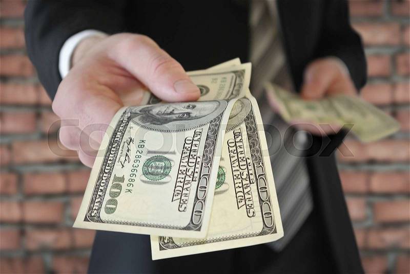 A man in a business suit offers money, stock photo