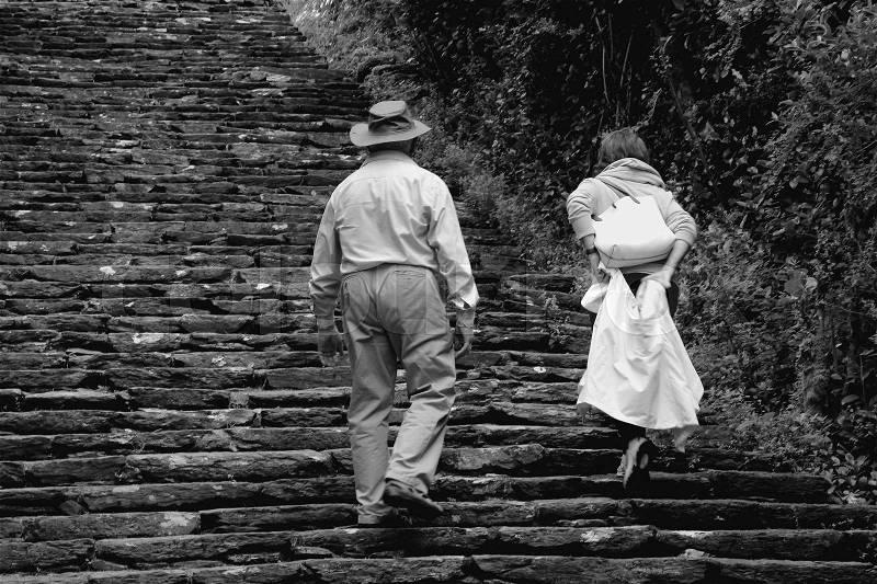 Couple, man and wife, walk on the steps in the Ilnacullin of Garinish Island in Ireland in the summer in black and white, stock photo
