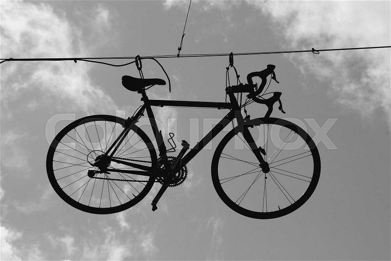 The bike hangs on the cable in the sky with clouds in the street of Killarney in Ireland in the summer in black and white, stock photo