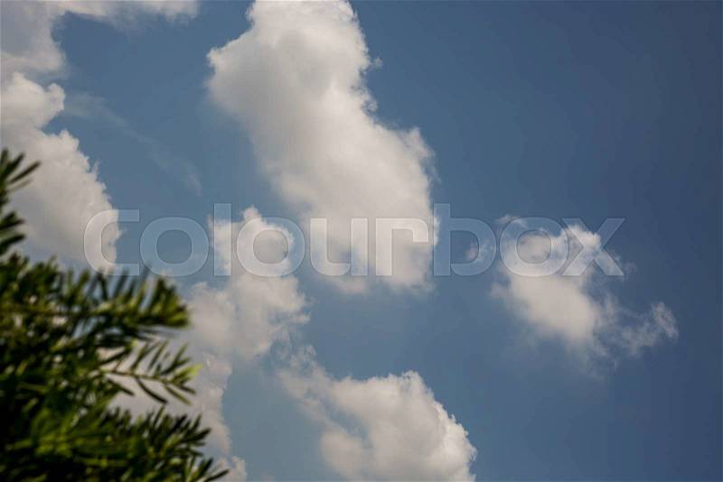 White fluffy clouds with tree blurred foreground, stock photo