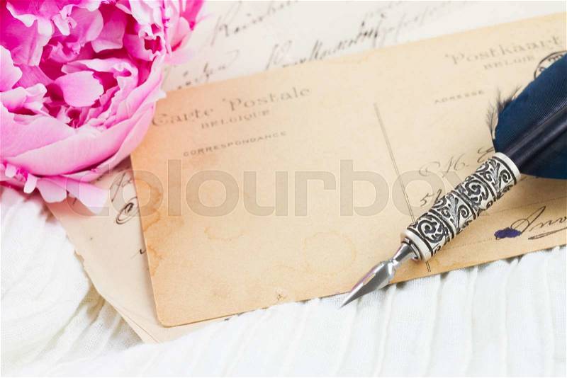 Pink peony with antique blank letter with copy space and feather pen on white lace background, stock photo