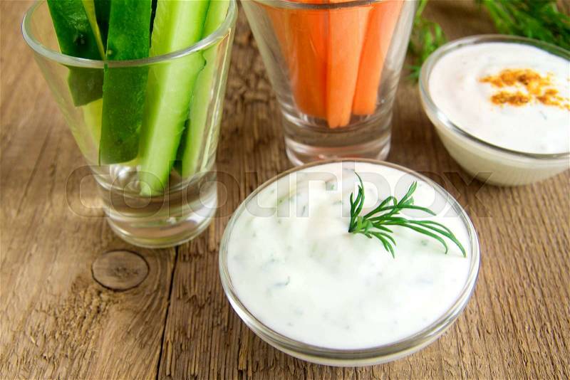 Fresh Greek Tzatziki yogurt dip (sauce) and assorted vegetables on wooden table, stock photo