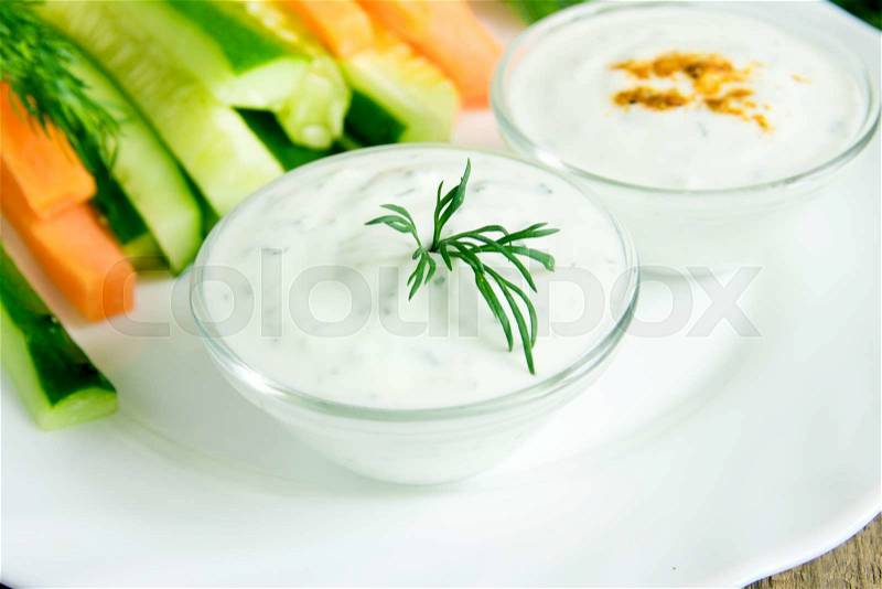 Fresh Greek Tzatziki yogurt dip (sauce) and assorted vegetables on white plate, stock photo