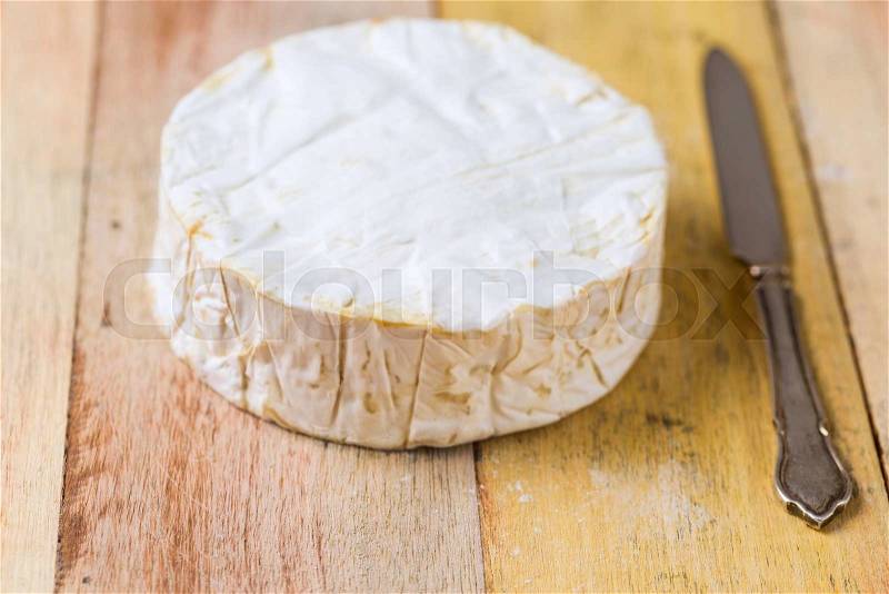 Camembert cheese and vintage knife on wooden table, stock photo