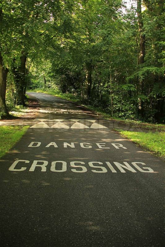 Attention, speed bump and the words, danger crossing at the asphalt in this area, stock photo