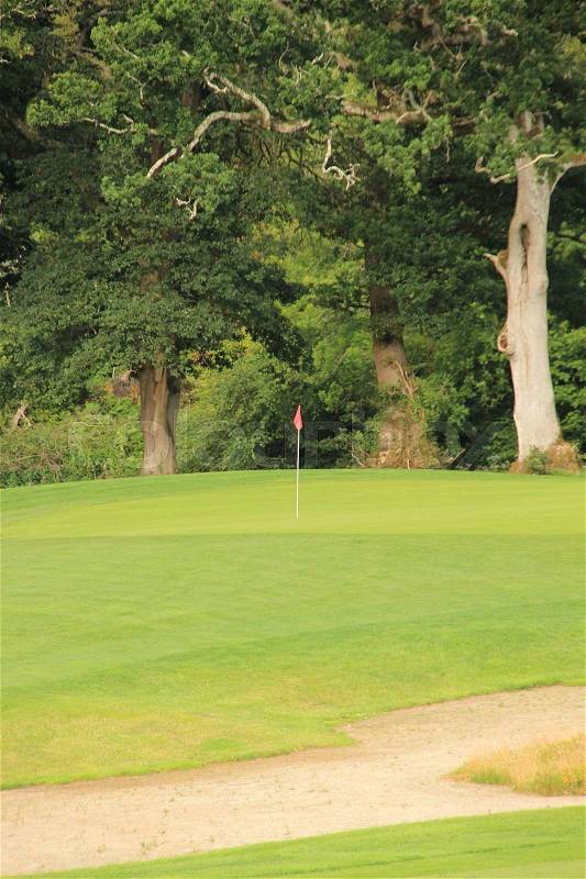 Golf field and a red flag in the hole in the summer, stock photo