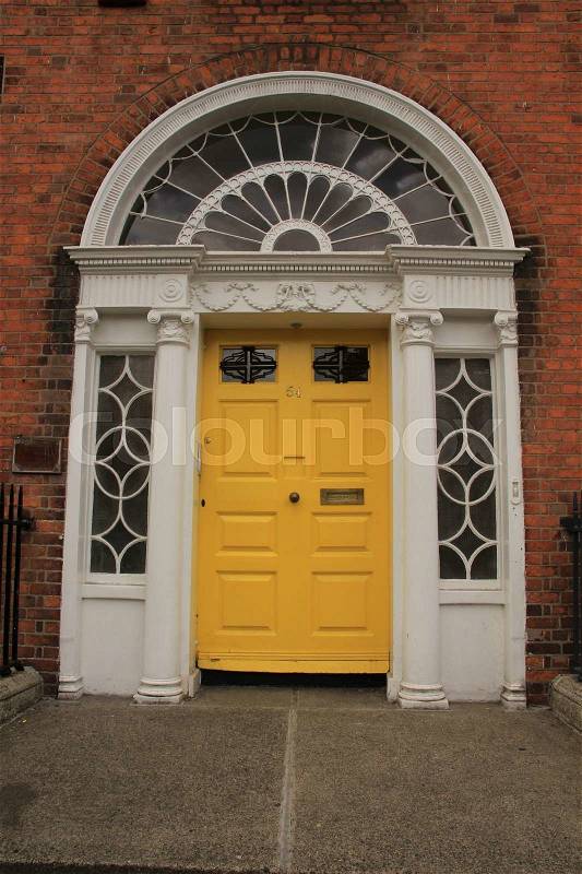 A striking yellow front door in one of the famous streets in the city Dublin in Ireland in the summer, stock photo