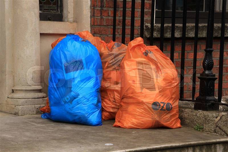 Waste in plastic bags, blue or orange before the front door of the building, stock photo