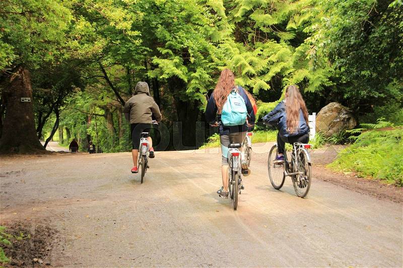 Four girls are biking in one of the gardens of Muckross House in Killarney National Park in Ireland in the summer, stock photo
