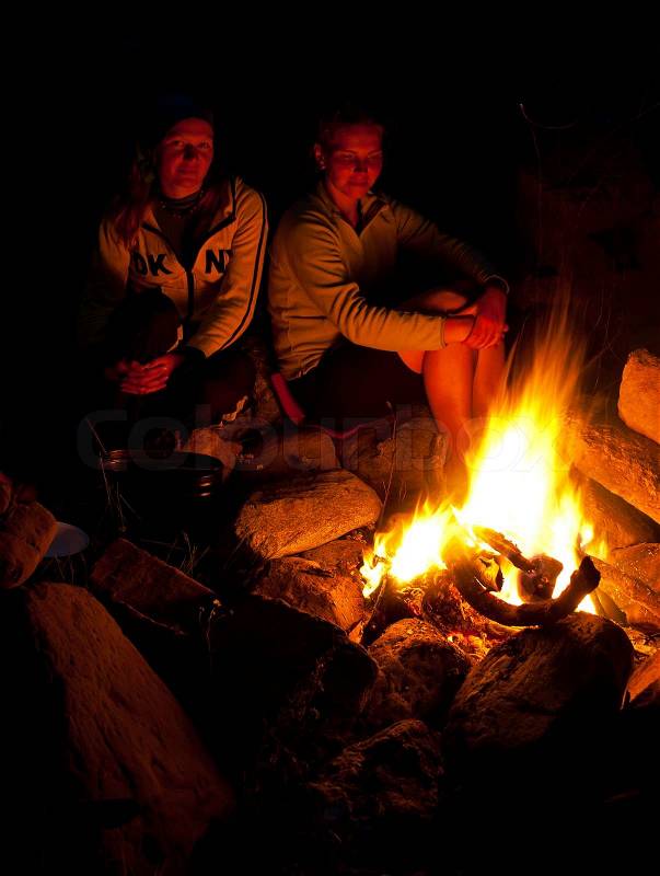 Group of backpackers relaxing near campfire after a hard day, tourist background, stock photo
